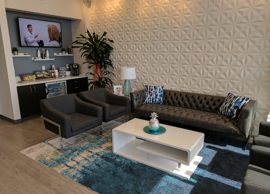 Smile Avenue waiting room with leather sofas, 3D accent wall, and complimentary refreshments